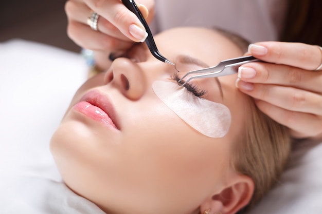 Eyelash extension procedure. woman eye with long eyelashes. lashes, close up, selected focus.