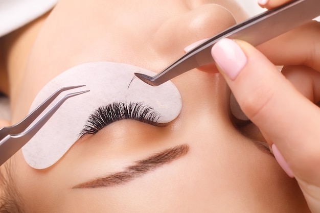 Eyelash Extension Procedure. Woman Eye with Long Eyelashes.