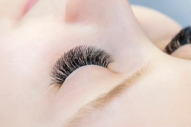 Eyelash extensions. Closeup of eyes with extended eyelashes and without extended eyelashes, white girl. before and after