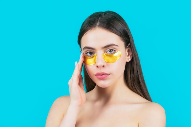 Eyes mask cosmetic patches woman face closeup Woman applying golden eye patches Close up portrait girl Portrait of beauty woman with eye patches showing an effect of perfect skin