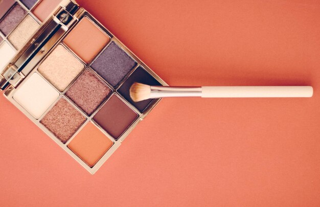 Eyeshadow palette and makeup brush on orange background eye shadows cosmetics product as luxury beauty brand promotion and holiday fashion blog design