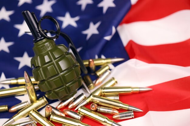 F1 frag grenade and many yellow bullets and cartridges on United States flag. Concept of gun trafficking on USA territory or special operations