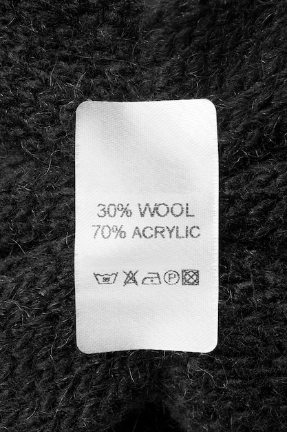 Fabric composition and care instructions clothing label on\
black knit background