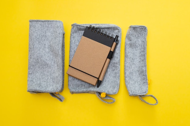 Fabric pencil cases with notepad on yellow background