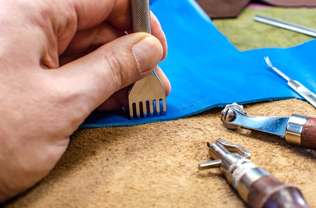 Fabricageproces van lederwaren. Gereedschap voor het naaien van tassen, portefeuilles, koppelingen. Gekleurde stukken leer. Detailopname