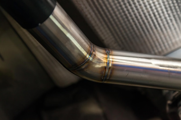 Photo fabrication and installation of a stainless steel car exhaust pipe with a bifurcation and a louder sound with a color weld under bottom tuning and auto service industry