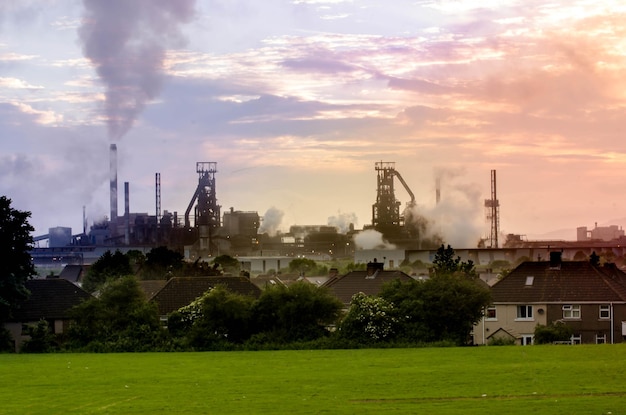 Foto fabriek die rook uitzendt door grasveld tegen de hemel tijdens zonsondergang