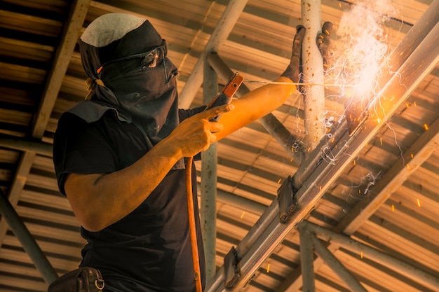 Fabrieksarbeider bij het lassen van het fabrieksstaal onder het dak