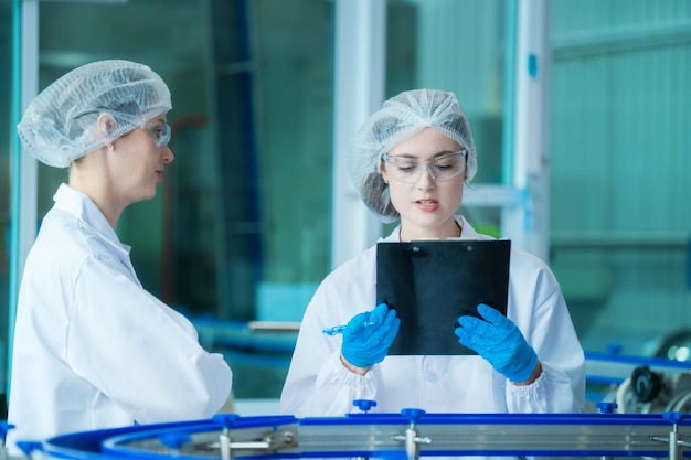 Foto fabrieksarbeider controleert waterflessen in het magazijn van de industriële fabriek