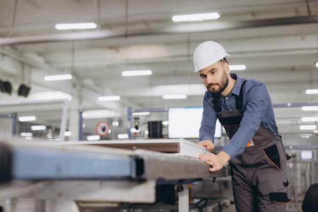 Fabrieksarbeider die de productie van aluminium vensterframes controleert
