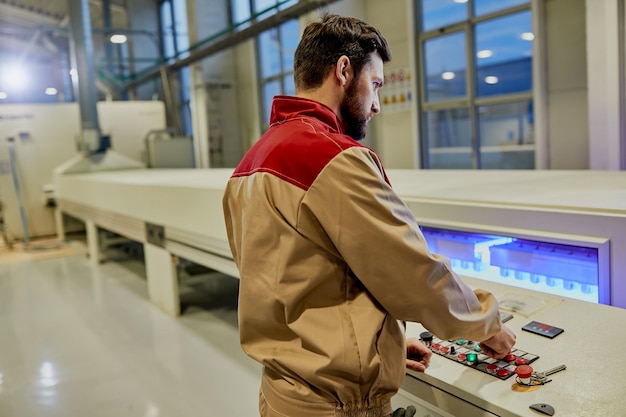 Fabrieksarbeider die een geautomatiseerde machine bedient voor houtverwerking in een fabriek