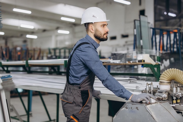Fabrieksarbeider die machines bedient voor de productie van vensters en deuren van aluminium en pvc