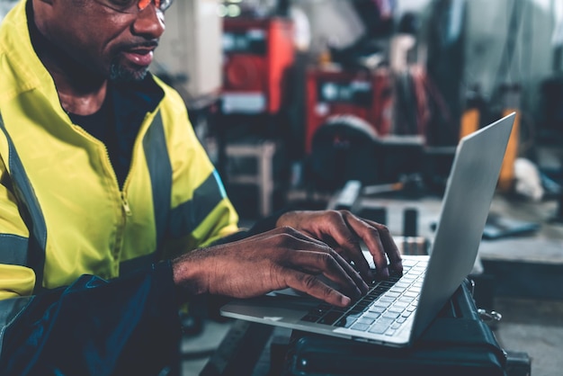Fabrieksarbeider die met laptop computer werkt om bedreven procedurecontrolelijst te doen