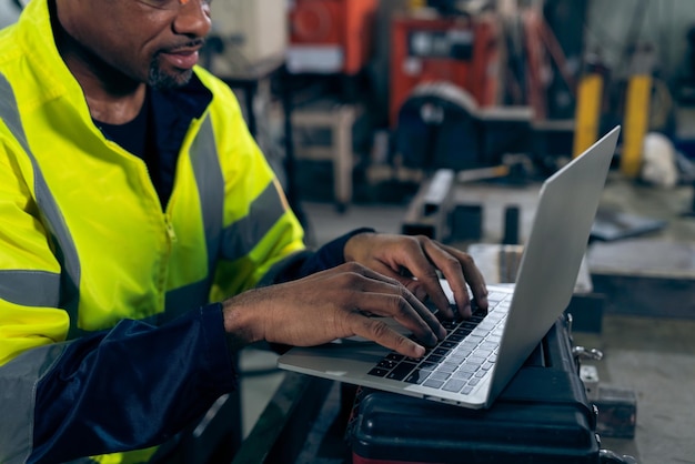 Fabrieksarbeider die met laptop computer werkt om bedreven procedurecontrolelijst te doen