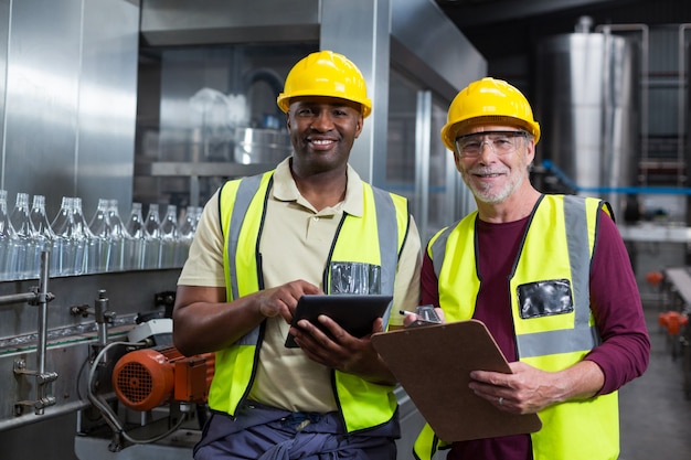 Fabrieksarbeiders met klembord en digitale tablet werken in de fabriek