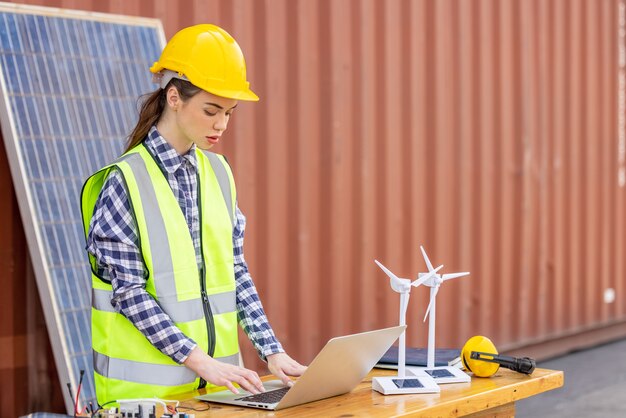 Fabrieksarbeiders of ingenieurs die een gloeilamp vasthouden en een tabletcomputer gebruiken met een windmolenmodel