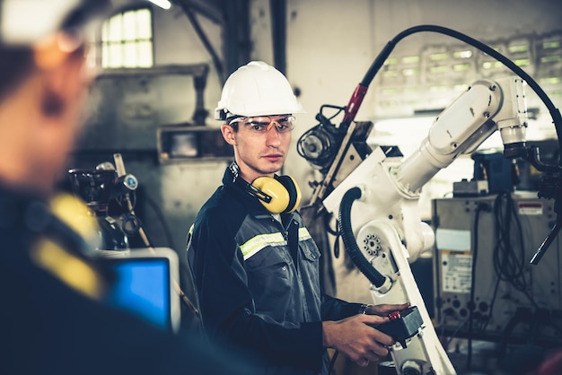 Fabrieksarbeiders werken met bedreven robotarm in een werkplaats