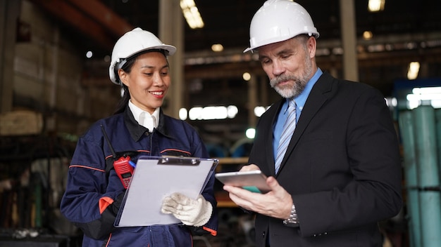 Fabrieksmanager en vrouwelijke ingenieur in fabriek en inspecterende fabriek op achtergrond van industriële fabrieken