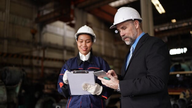 Fabrieksmanager en vrouwelijke ingenieur in fabriek en inspecterende fabriek op achtergrond van industriële fabrieken