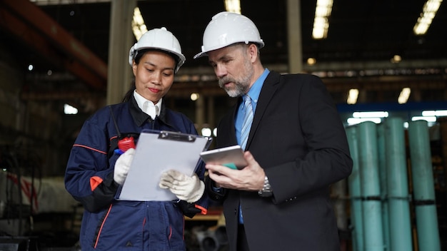 Foto fabrieksmanager en vrouwelijke ingenieur in fabriek en inspecterende fabriek op achtergrond van industriële fabrieken