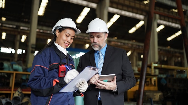 Fabrieksmanager en vrouwelijke ingenieur in fabriek en inspecterende fabriek op achtergrond van industriële fabrieken