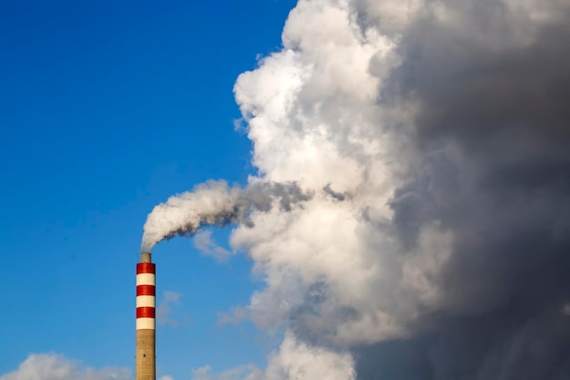 Fabrieksschoorsteenrook met blauwe lucht en wolken