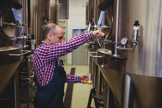 Foto fabrikant gieten bier in glas bij brouwerij