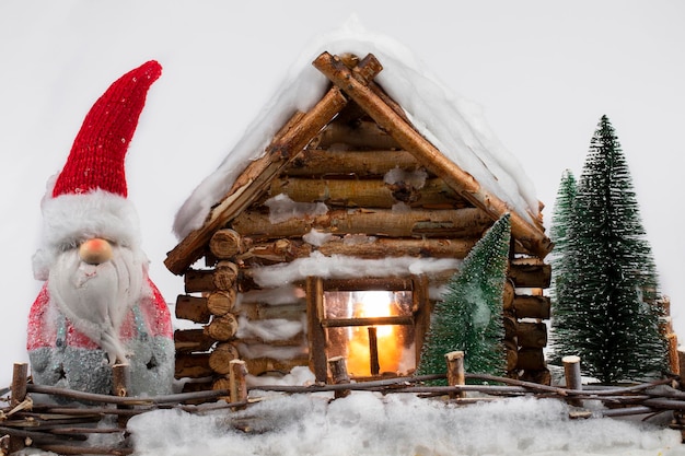 Сказочный рождественский гном стоит рядом с миниатюрным деревянным домиком
