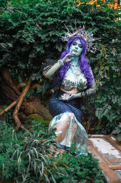 fabulous dark mermaid with blue skin in the forest closeup