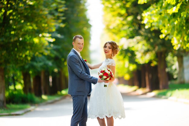 Fabulous young wedding couple posing in the park on the sunny day.