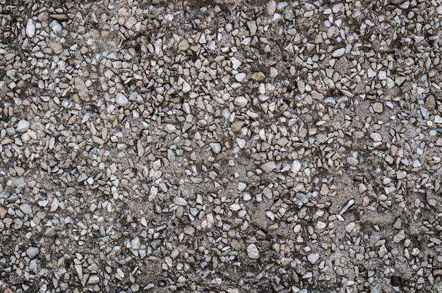 Facade of building  fragment of wall with inclusions of gray stone pebbles in black asphalt