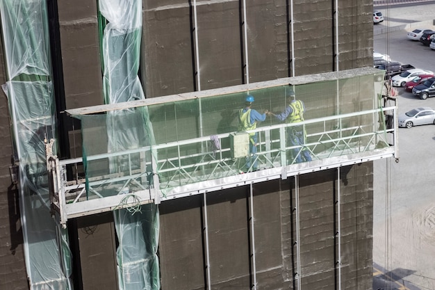 Photo facade cladding of the building by the builders on an overhead crane