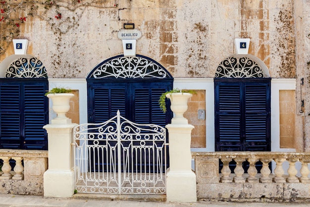 몰타(Malta)의 엠디나(Mdina) 시에 있는 푸른 나무 창문과 문이 있는 집의 외관. 몰타 섬의 광경