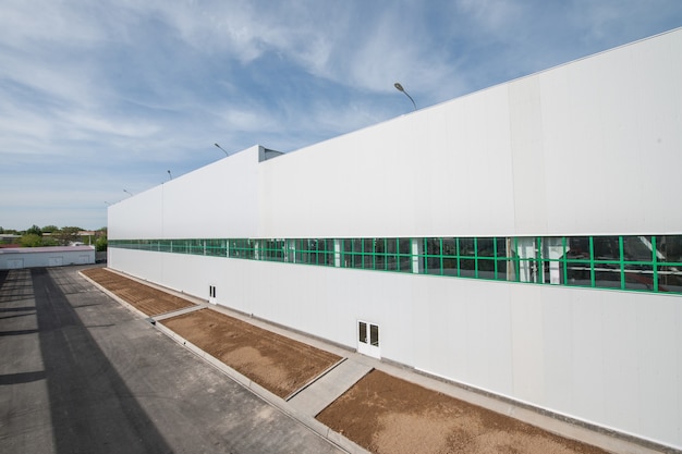 Facade of an industrial building and warehouse in length with a place for flower beds and plants