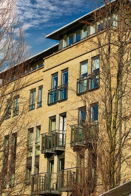 Facade of a modern apartment building with balconies framed by leafless trees against a clear blue sky in Harrogate England