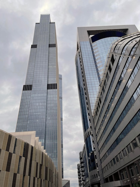 Facade of modern skyscraper with glass walls From below of contemporary tall skyscraper with glass walls against cloudy sky in downtown