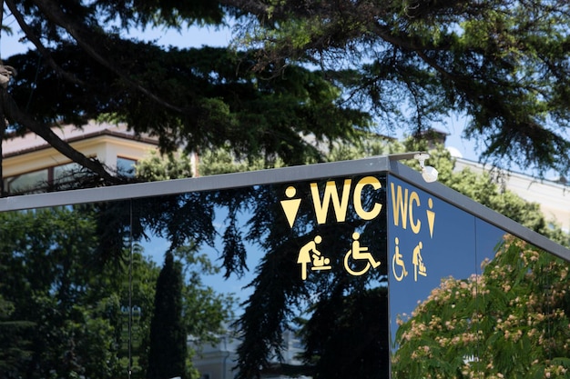 The facade of a modern toilet on a city street with icons and symbols a disabled person a female a male a mother with children High quality photo