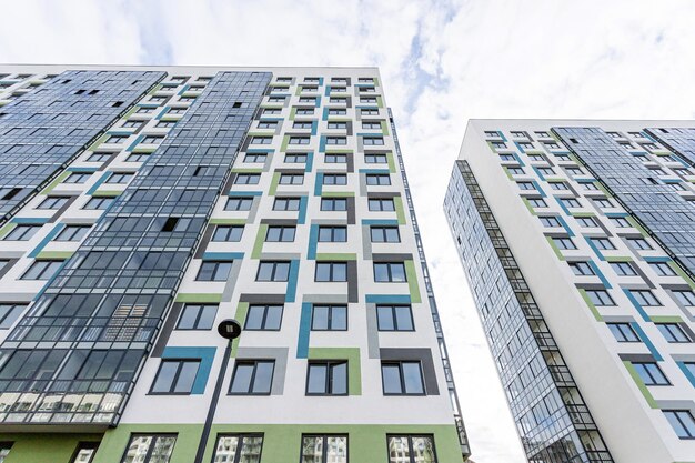 facade of a new building of white blue and green color with glass windows and balconies