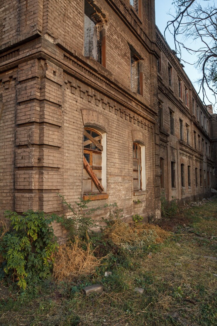 Фотография фасад старого заброшенного кирпичного дома с окном, облицованным деревянными досками