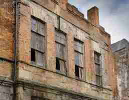 Photo facade of an old abondoned building boarded up windows old brick building