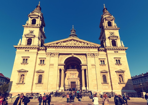 Фасад базилики Святого Стефана, также известной как Святой Иштван в Будапеште, Венгрия, с туристами и голубым небом. Путешествие на открытом воздухе на венгерском фоне