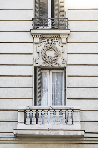 Facade of a vintage house with balconies with metal shutters and a balustrade made of facade material