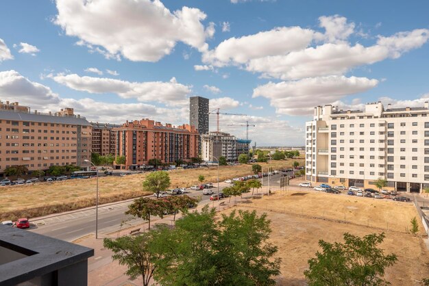 Facades of modern buildings and empty lots between them with blue skies with many clouds