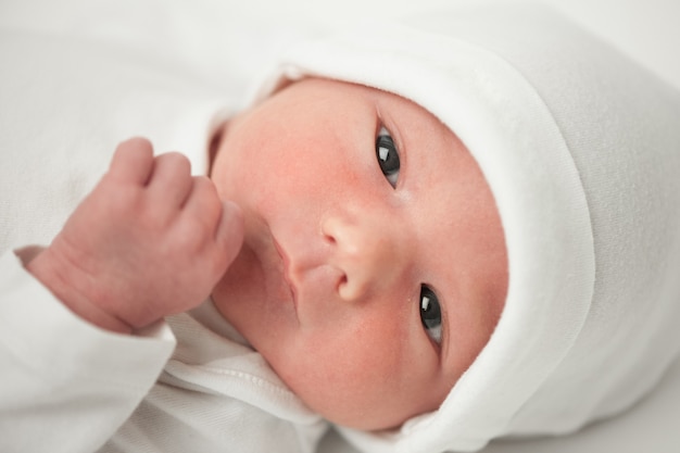 Faccia bambino con un cappello bianco su sfondo bianco