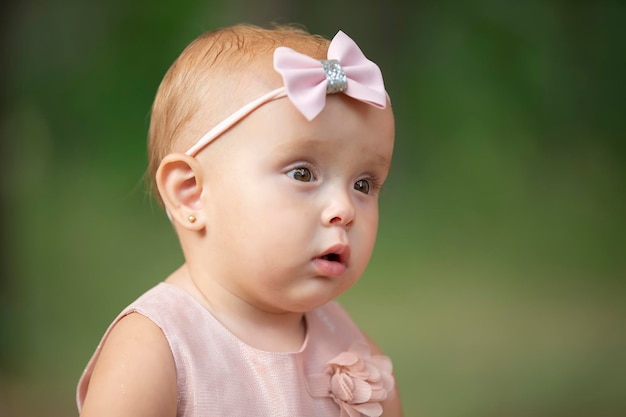 The face of a beautiful little girl on a green background One year old child