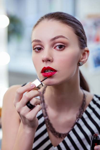  Face of a beautiful young woman putting on her lipstick