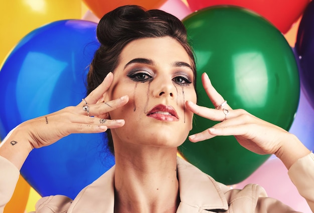 Face beauty and makeup with a model woman in studio against a balloon background for fashion or style Portrait party and sad with an attractive young female posing with balloons at a birthday