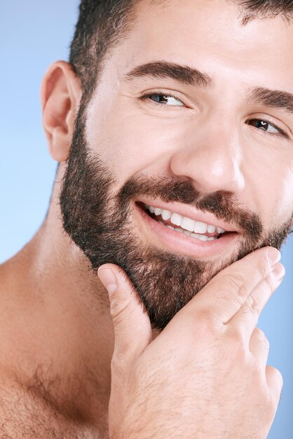 Foto bellezza del viso e cura della pelle con un modello uomo in studio su sfondo blu per il benessere naturale o la cura della barba idea barba e pelle con un bel giovane maschio che pensa a cosmetici o trattamenti