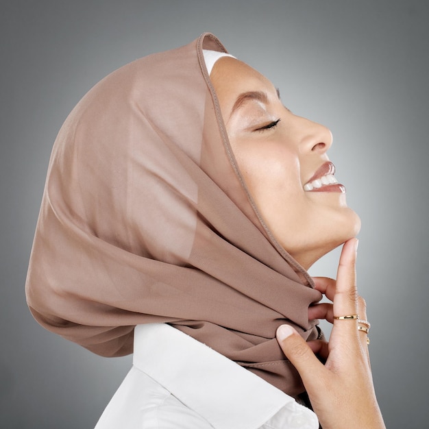 회색 배경에 스튜디오에서 히잡을 쓴 여성 무슬림과 얼굴 미용 또는 피부 관리 건강을 증진하기 위해 머리 스카프를 두른 이슬람 여성과 함께 행복하고 피부가 자연스러운 건강 화장품