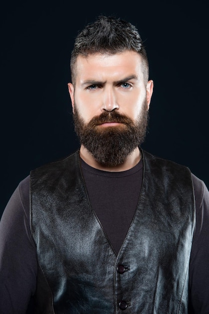 Face of brutal bearded man in leather on black background